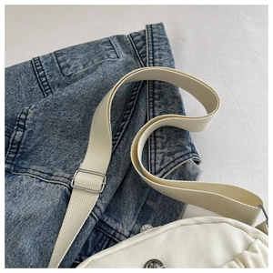 Detail of white canvas bag showing adjustable silver buckle and durable webbing strap