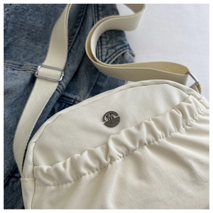 Macro shot of cream nylon handbag showing drawstring pleats and gunmetal logo detail