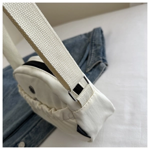 Detail of white nylon crossbody bag featuring wide woven strap and pleated zipper pocket