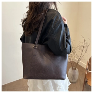 Dettaglio della borsa shopper marrone scuro in ecopelle martellata con anelli dorati