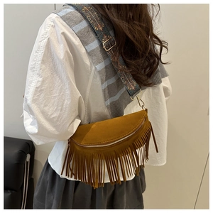 Close-up of mustard yellow suede tassel bag with ethnic style jacquard wide shoulder strap