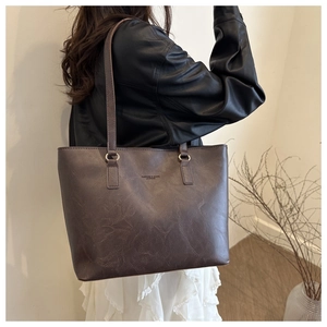 Detail of dark brown leather tote bag with vintage texture and embossed lettering