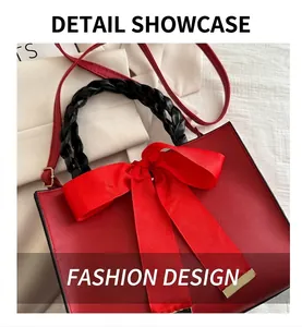 Close-up of red leather handbag with black woven handle and a large grosgrain bow