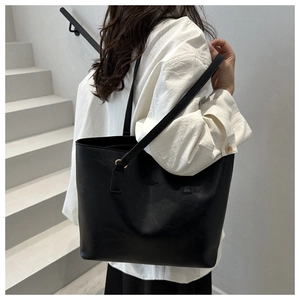 Minimalist black matte leather tote bag with subtle logo detail for daily commuting