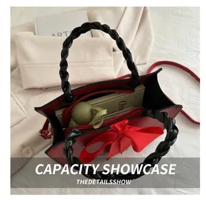 Detail of red bow handbag showing interior storage for books and umbrella