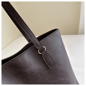 Detail of dark brown leather tote with fine litchi grain and gold ring strap connector