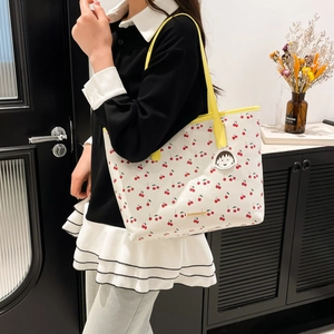 Cute cherry print tote bag with yellow handles and a cartoon character pendant on a model