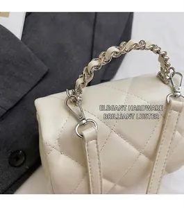 Détail d'un sac cylindrique matelassé blanc avec ferrures argentées et chaîne