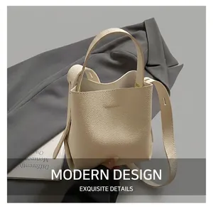 Gros plan sur le sac seau en cuir grainé blanc cassé avec poignée et logo gravé