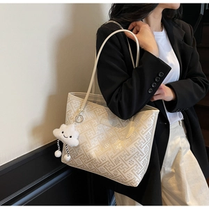 Detail of cream tote bag featuring geometric patterns and a cute white cloud pendant