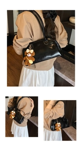 Detailed view of black oil wax leather shoulder bag with a cute plush bear charm