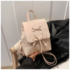 Detail eines rosa PU-Leder-Minirucksacks mit Schleifenkordelzug auf einem Vintage-Holzstuhl