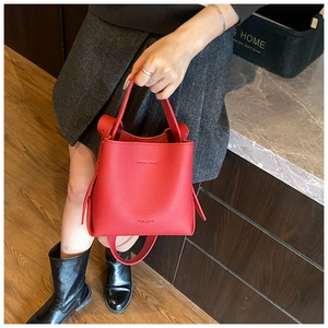 Détail du sac seau rouge en cuir grainé avec poignée et bandoulière amovible