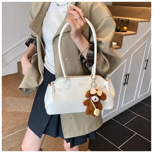 Close-up of white wax leather shoulder bag with a cute brown plush bear charm