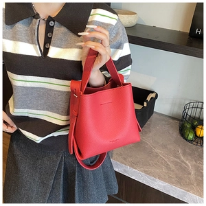 Vue latérale du sac seau rouge en cuir grainé avec poignée et bandoulière assortie
