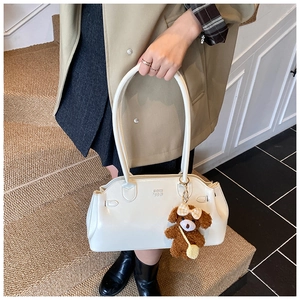 Detail of cream white leather handbag with logo and cute brown teddy bear pendant