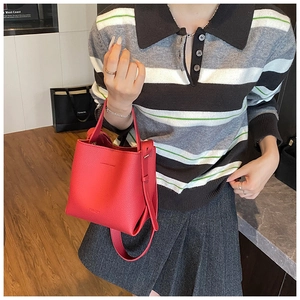 Vue détaillée du sac seau en cuir rouge avec texture grainée et boucle métallique