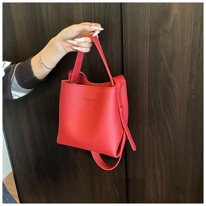 Détail du sac seau en cuir rouge à grain litchi avec marquage de la marque en relief