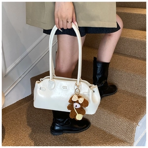 Detail of white leather shoulder bag with embossed logo and brown plush bear charm