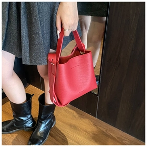 Détail de la texture cuir grainé rouge sur un sac seau avec poignée supérieure