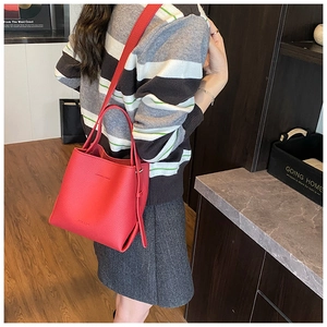 Vue détaillée d'un sac seau en cuir rouge à texture litchi porté par un modèle
