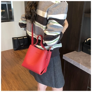 Vue détaillée d'un sac seau en cuir rouge vif porté par un mannequin dans une boutique