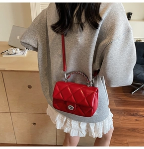 Détail du sac rouge matelassé à losanges avec fermoir argenté et bandoulière en cuir