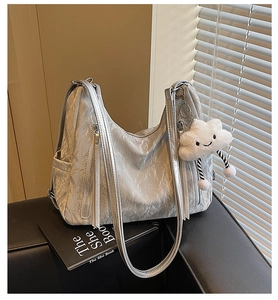 Chic silver hobo bag with pleated texture and cloud charm on black sofa setting