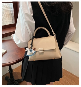 Détail d'un sac beige avec fermoir métallique et breloque cheval à bascule mignonne