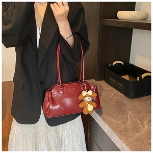 Detail of vintage dark red faux leather tote bag with cute brown plush bear charm