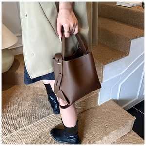 Détail du sac seau en cuir marron foncé avec ferrures dorées et sangles latérales