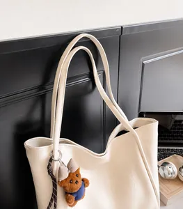 Detail of soft cream tote bag with adjustable shoulder straps and cute bear pendant accessory