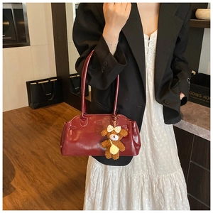 Detail of vintage burgundy oil wax leather handbag with cute plush bear charm accessory