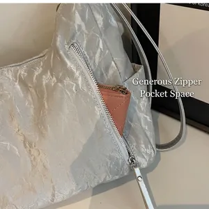 Detail of silver-grey pleated fabric shoulder bag showing a pink wallet in the front pocket