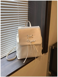 Detailansicht eines weißen PU-Leder-Rucksacks mit Schnürschleife und Metallösen auf Fensterbank
