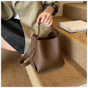 Détail du sac seau marron à motif litchi montrant la bandoulière et la texture du cuir