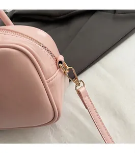 Close-up of light pink handbag showing gold zipper hardware and fine PU leather stitching