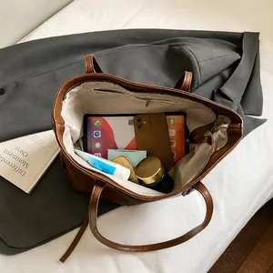 Interior view of large brown tote bag showing organized storage for gadgets and cosmetics
