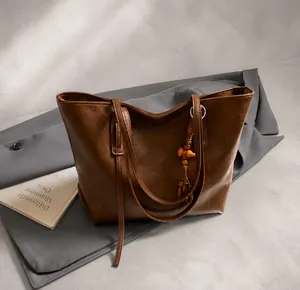 Brown oil wax leather tote bag featuring a decorative wooden bead tassel detail