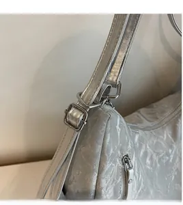 Detailed view of the adjustable long shoulder strap and silver wrinkled texture of the tote bag