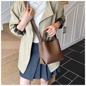 Détails de la texture du cuir marron foncé grainé et coutures sur le sac seau