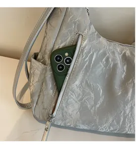 Detail of silver pleated shoulder bag showing functional zipper pocket for smartphone