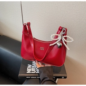 Close-up of bright red underarm bag with pearl bow charm and silver COIH 2DN branding