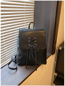 Detail eines schwarzen Lederrucksacks mit Schnürung auf einer dunklen Fensterbank