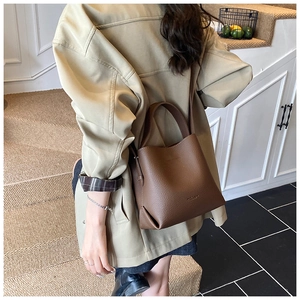 Sac seau en cuir grainé marron avec poignée et bandoulière dans un décor de style de vie