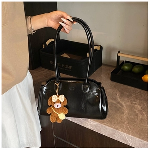 Detail of vintage oil wax leather handbag with polished finish and plush bear pendant