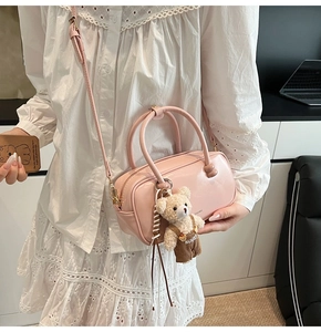 Pink patent leather cylindrical handbag with a cute teddy bear charm and adjustable strap