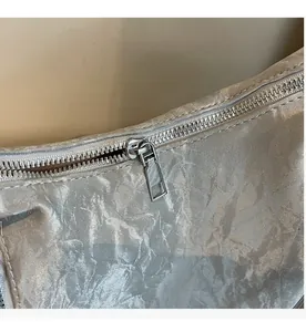 Detail of silver metallic textured fabric and smooth metal zipper on the bag