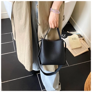 Détail du sac seau en cuir grainé noir avec poignées et bandoulière réglable