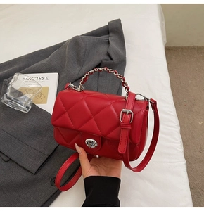 Détail du sac matelassé rouge avec poignée en chaîne argentée et fermoir pivotant